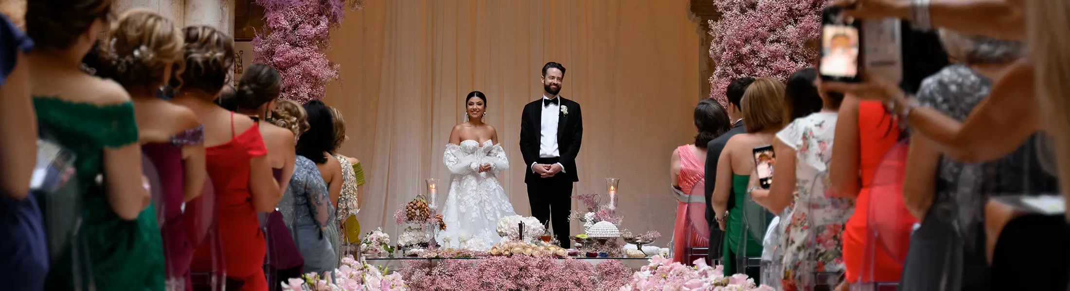 Couple exchanging personalized vows during a symbolic wedding ceremony surrounded by flowers and guests